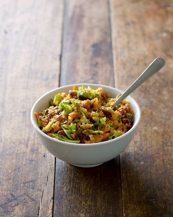 Apple quinoa salad in a white bowl with a spoon.