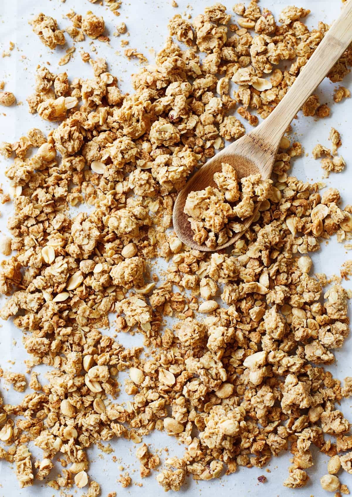Granola on a white surface and on a wooden spoon.