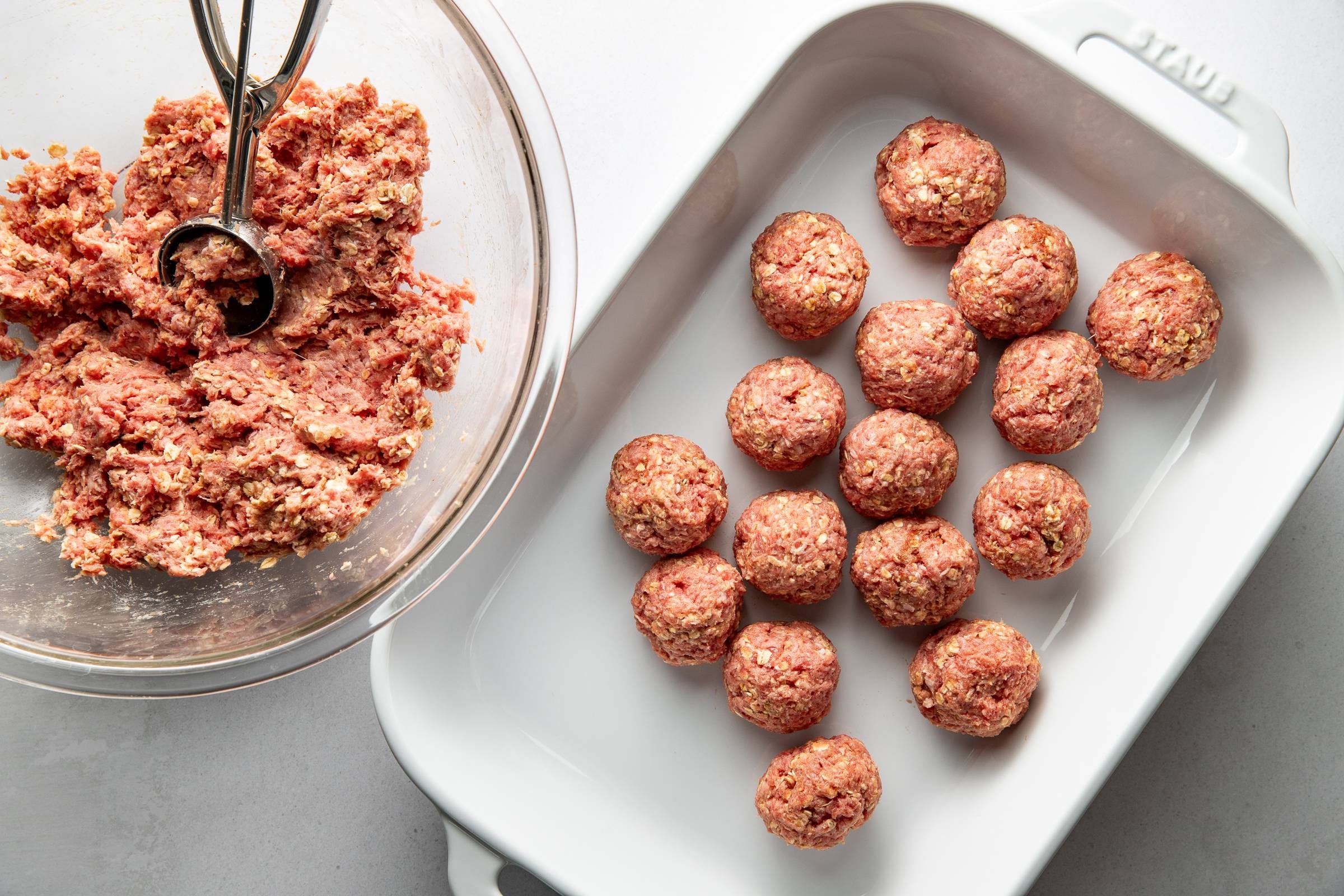 Mixed meatballs rolled into a casserole dish.