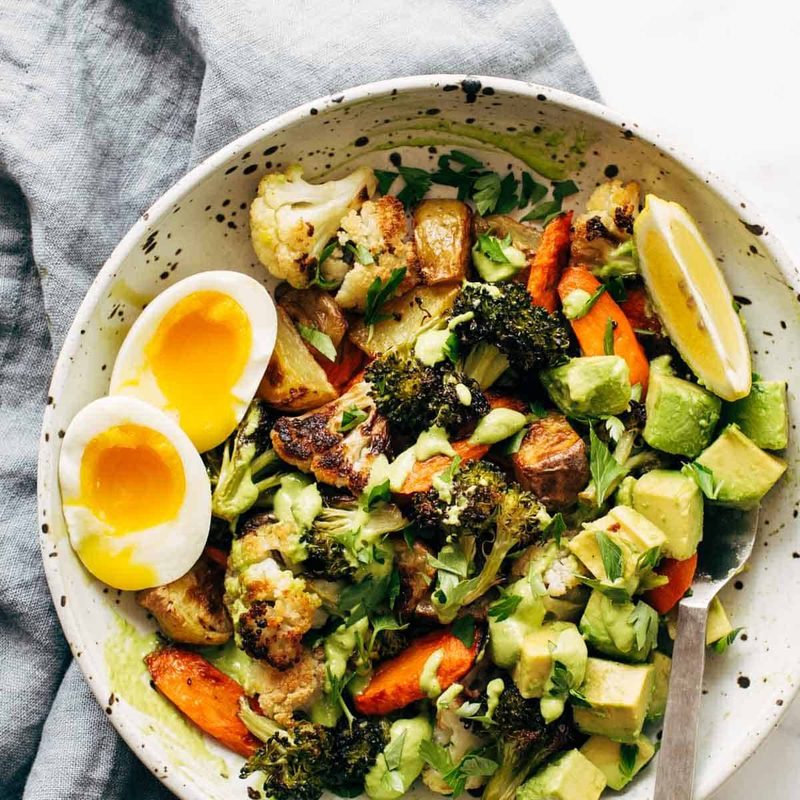 Roasted Vegetable Bowls with Green Tahini and a side of egg and a spoon in the bowl.