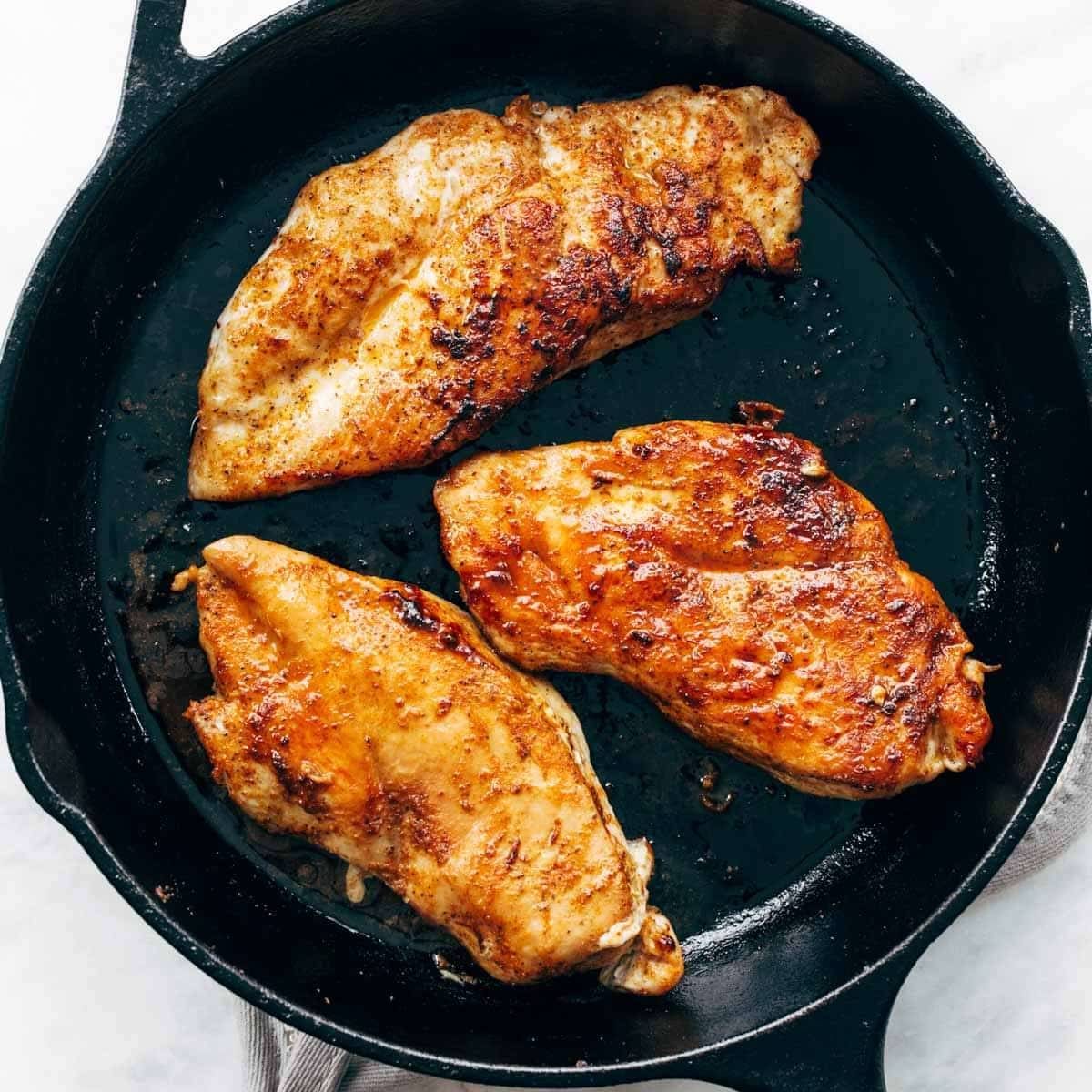 Chicken breasts in cast iron pan.
