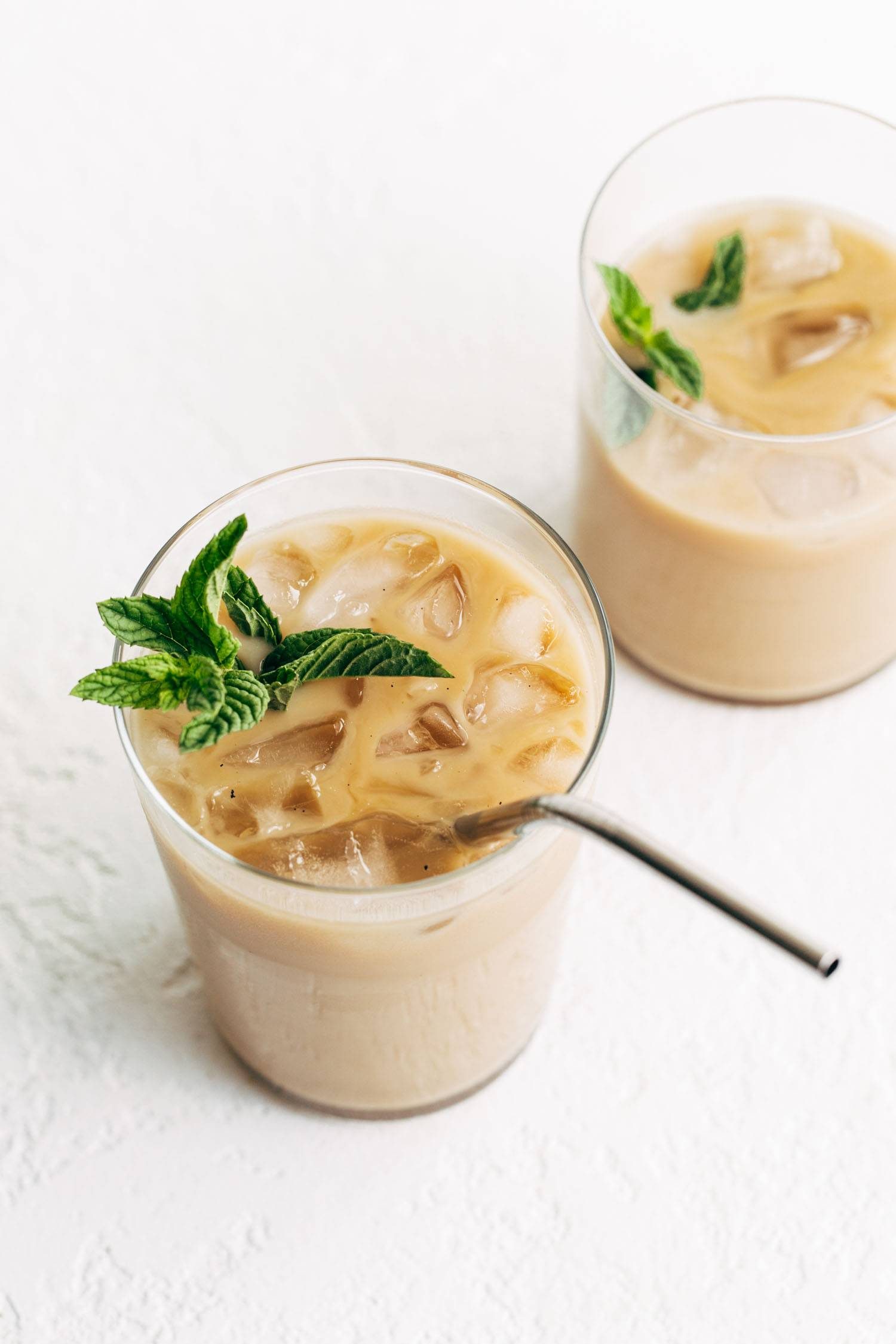 Vanilla mint iced coffee in two glasses, one with a metal straw.